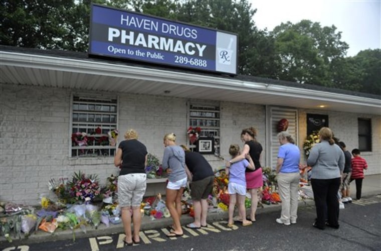 People bring flowers to Haven Drugs pharmacy where four people were killed during a botched weekend painkiller robbery in Medford, N.Y. 